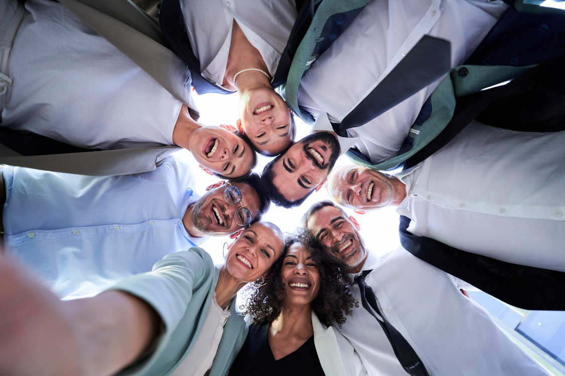 A group of people standing in a circle together facing the camera