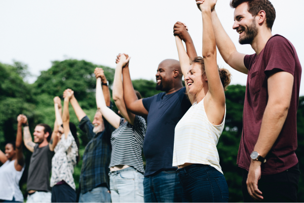 People standing together raising held hands and smiling